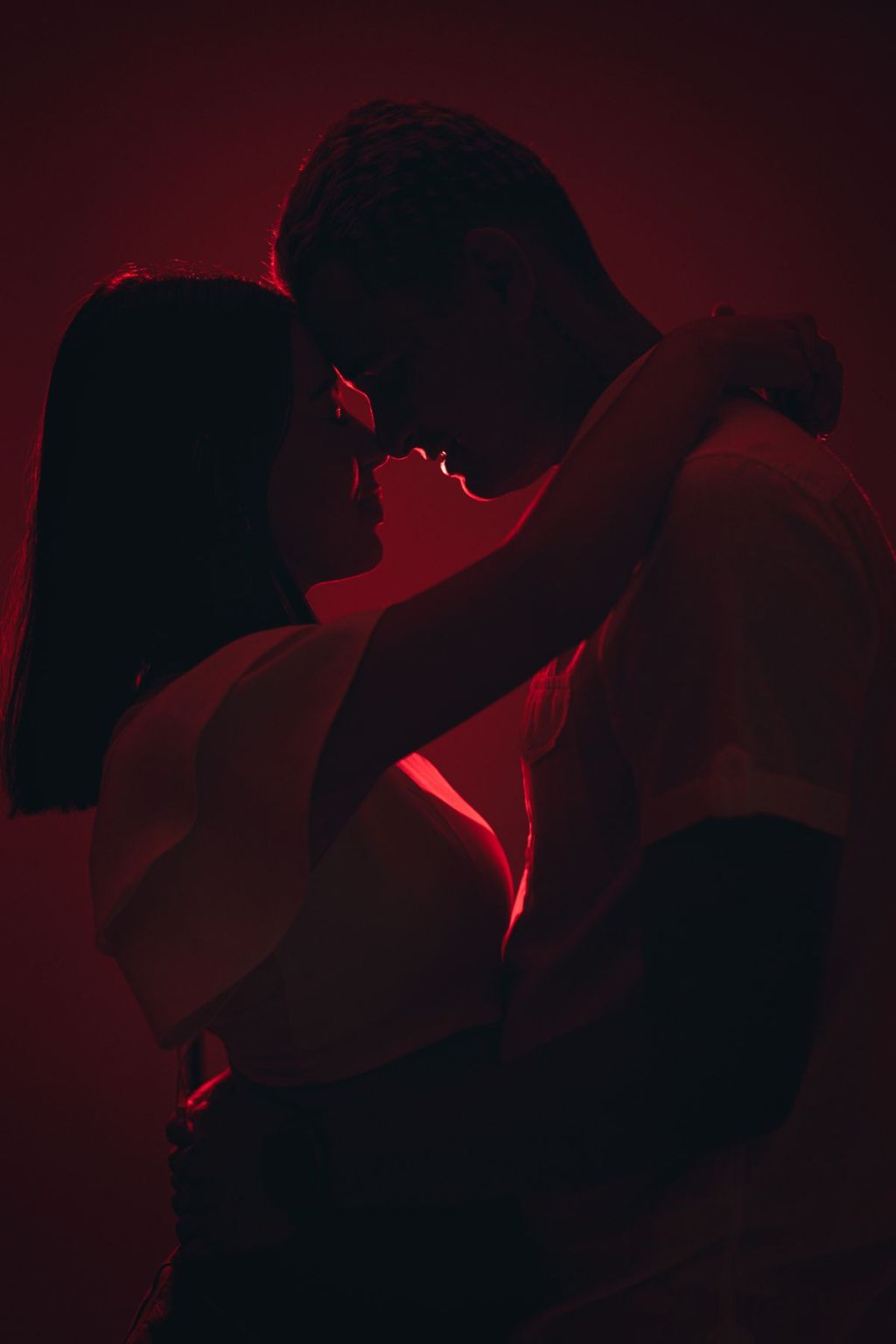 Silhuetas de um casal se abraçando em iluminação quente e escura.